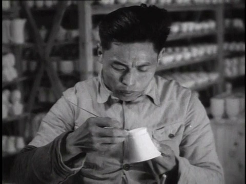 1944年，MS工人坐在工厂长凳上制作瓷杯，其他工人在后面/中国视频素材