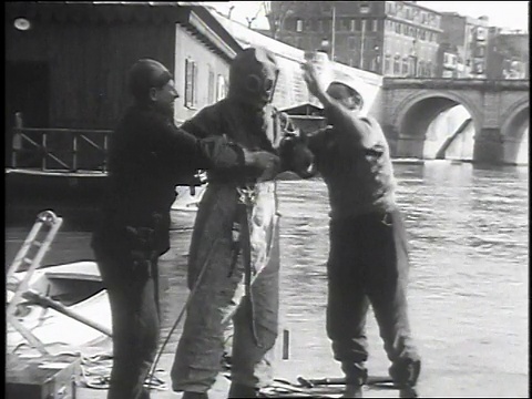 1930年，在意大利罗马，帮助发明家穿上特殊水服的人视频素材