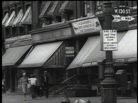 1939年，美国纽约市西130街，公共汽车与行人一起经过商店门面视频素材