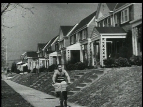 1948年，LS骑着自行车送报纸的男孩在一个居民区街道上送报纸/美国视频素材