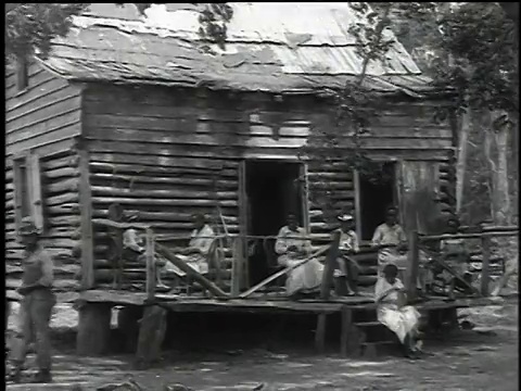 1916蒙太奇一家坐在一间小屋的门廊上编织篮子/刚果民主共和国视频素材