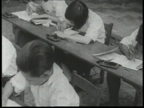 1932年HA中国男孩坐在桌子上在纸上写字/中国视频素材