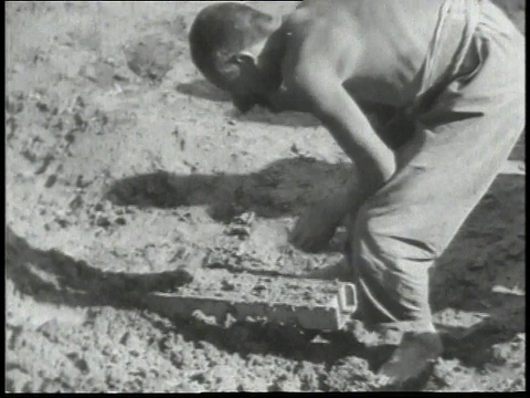 1938年，蒙太奇赤膊男子把泥浆捣成模具，形成泥砖/中国视频素材