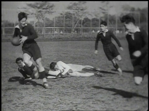 1939年，在一场橄榄球/日本比赛中，蒙太奇球员在地上踢足球，然后两队进行比赛视频素材