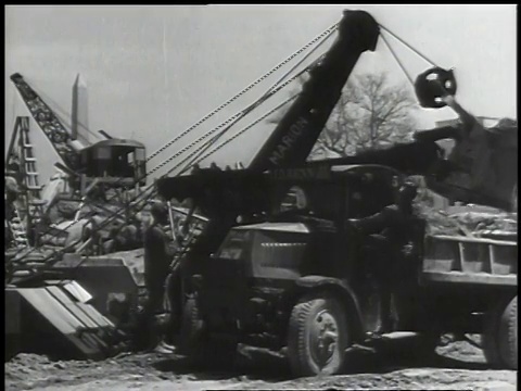 1941年，蒙太奇操作者在铲挖掘和装载泥土从地面到挖掘地点为新建筑和其他建筑设备/华盛顿特区视频素材