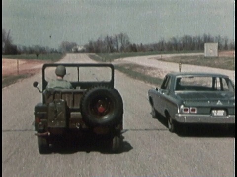 1960年代POV一辆吉普车沿着铺好的道路行驶，经过一辆民用汽车视频素材