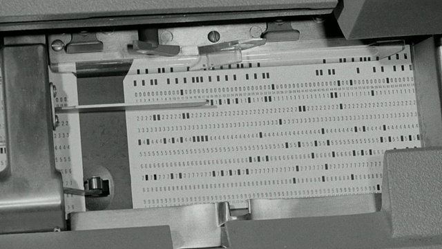 1969蒙太奇一间工业零件库存储藏室，和计算机技术人员输入数据指令和穿孔卡片机处理信息/联合王国视频素材