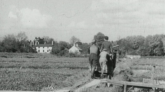 1933年，英国蒙太奇农场工人推着大车从水床之间的高架路上采摘西洋菜视频素材