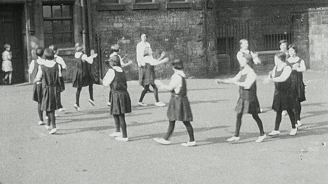 1925年，蒙太奇女学生在音乐课上展示黑板上的音符，老师在钢琴上弹奏音符，女学生穿着运动衣在操场上做健美操，英国泰恩郡纽卡斯尔视频素材