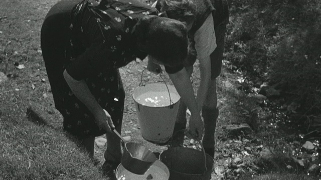 1944年蒙太奇母亲和孩子们从泉水中往桶里灌水，把水带回家，往浴缸里灌水，洗衣服/英国苏格兰阿奇里斯吉尔视频素材