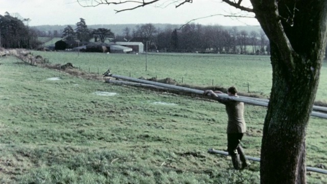 1967年，在英国一个牧场上运送泥浆输送管道的农民视频素材