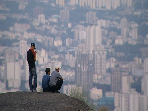 三名男子从伊朗德黑兰的一个高地俯瞰广阔的城市景观视频素材