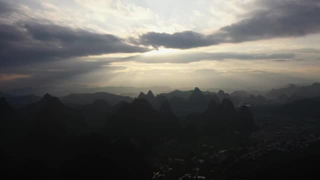 阳光透过乌云洒在群山之间的田野大地视频素材