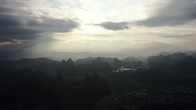 阳光透过乌云洒在群山之间的田野大地视频素材