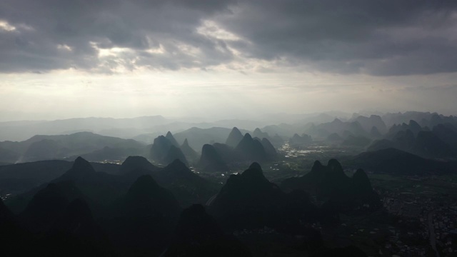 阳光透过乌云洒在群山之间的田野大地视频素材