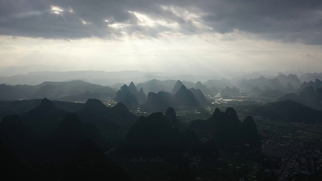 阳光透过乌云洒在群山之间的田野大地视频素材