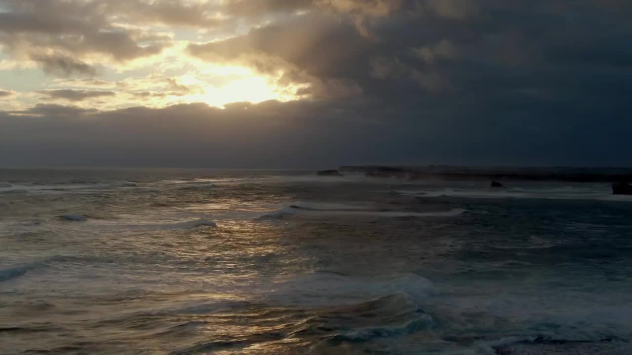 日落十分太阳被云层遮住了一半光线洒在海面海浪上，呈现出不一样视频素材