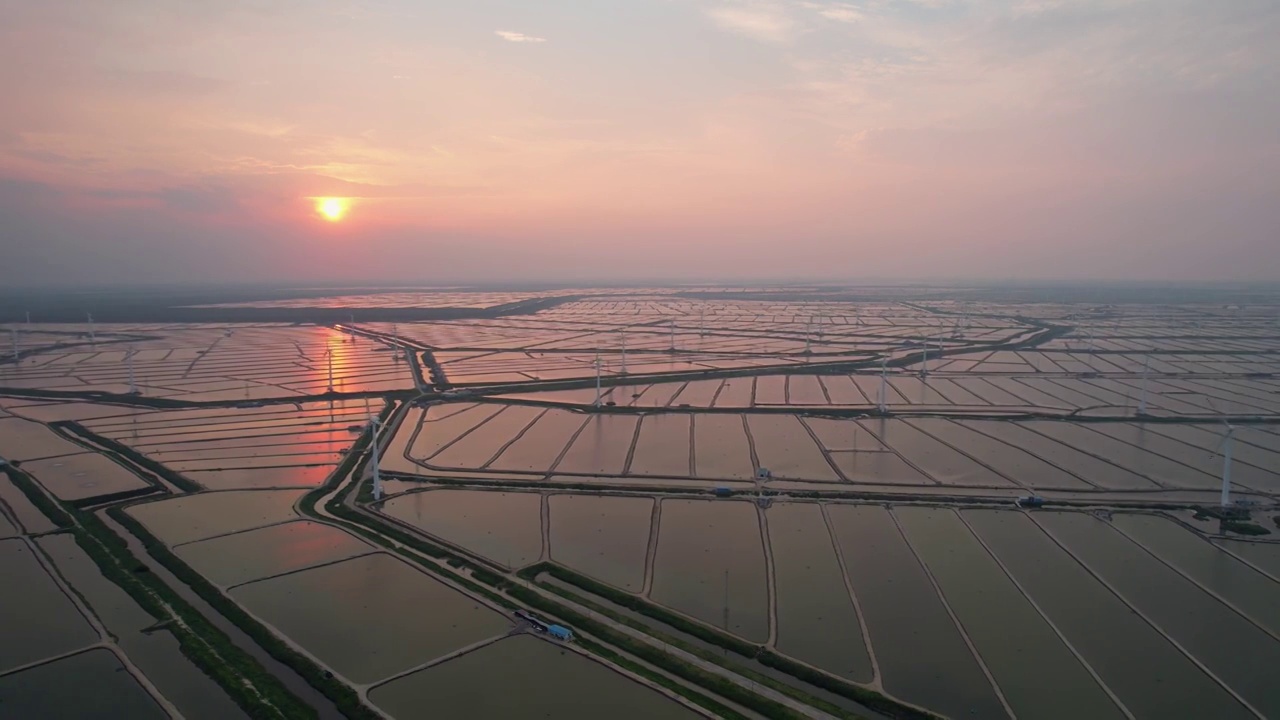 夕阳下海边滩涂上的风力发电机风车视频下载