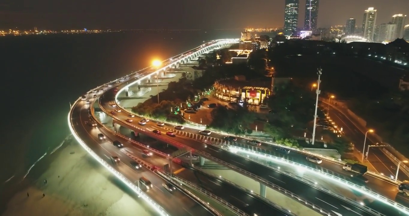 无人机拍摄了中国福建厦门市海边的交通和建筑物，夜间行驶的车辆和灯光明亮的建筑物视频素材