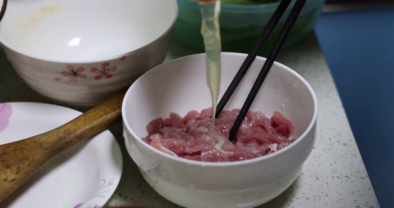 美食烹饪：把鸡蛋的蛋清倒入装满肉丝的碗里视频素材