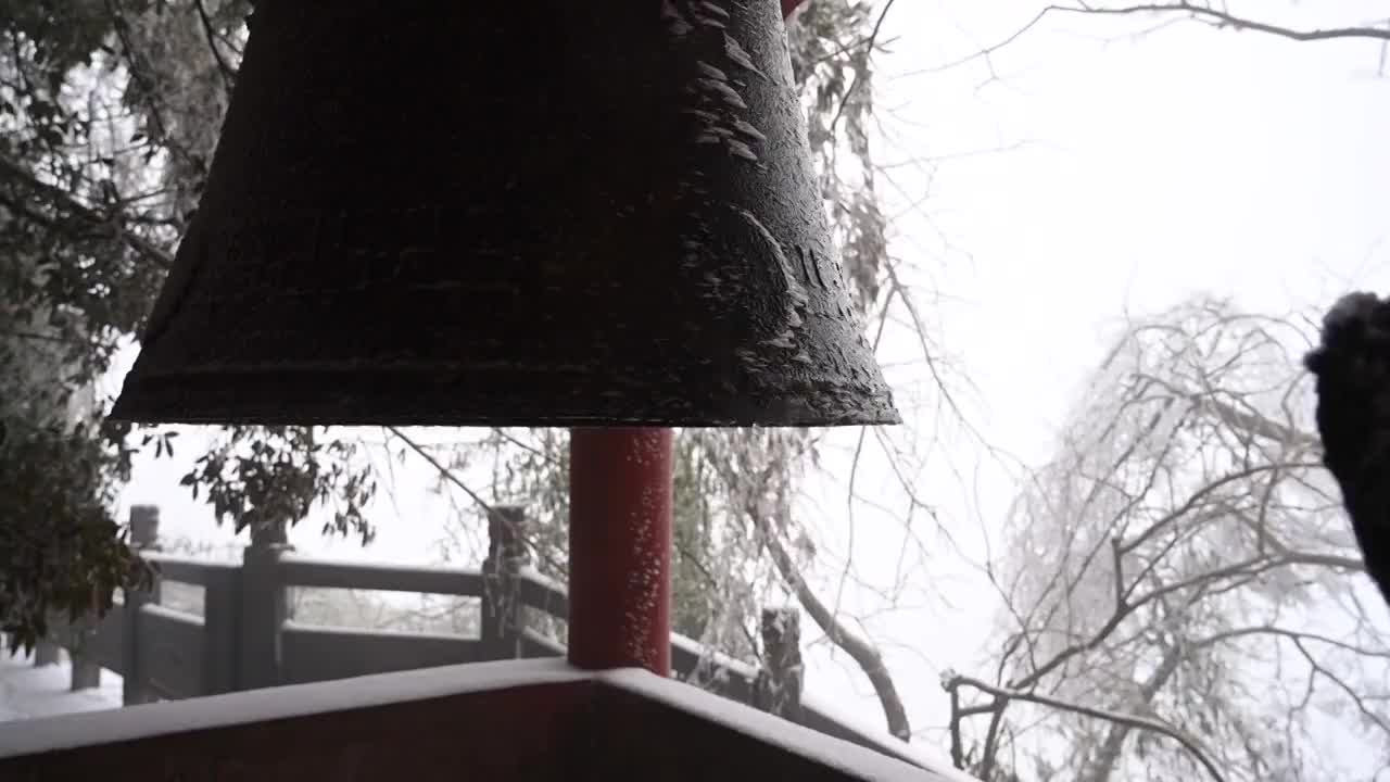 冬季大雪纷飞下的桂林八角寨寺庙里的撞钟视频素材