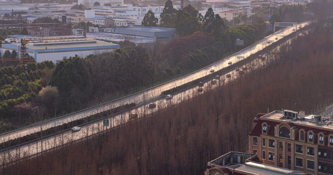 延时城市风景：夕阳下成灌高速上行驶的汽车与两边的建筑群视频素材