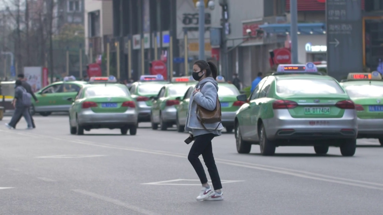 一个戴口罩的女孩在成都街头过马路视频素材