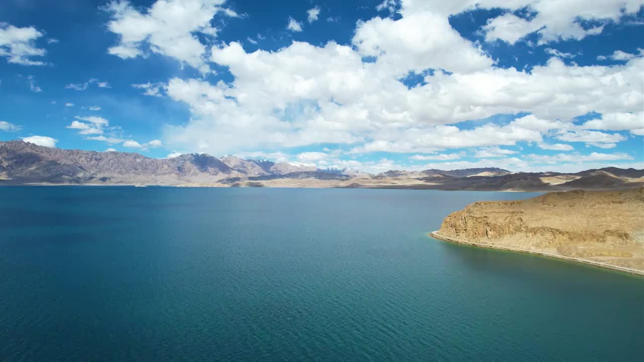 西藏阿里班公湖，六月晴朗的天气，航拍蓝天白云下，湖水湛蓝，雪山环抱，新藏公路从湖边经过。视频素材