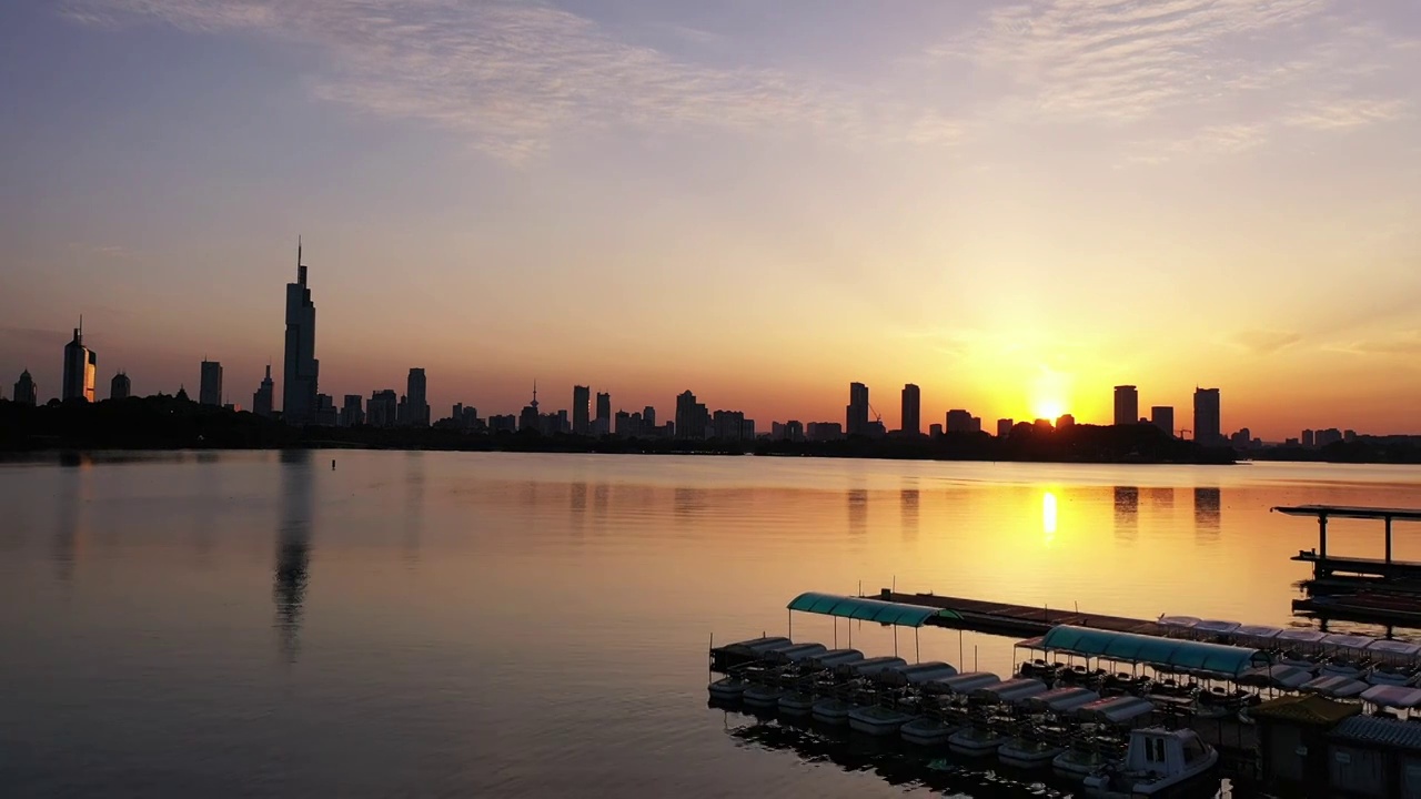 夏天日落时分夕阳下的南京玄武湖公园码头和城市天际线剪影的风光视频素材