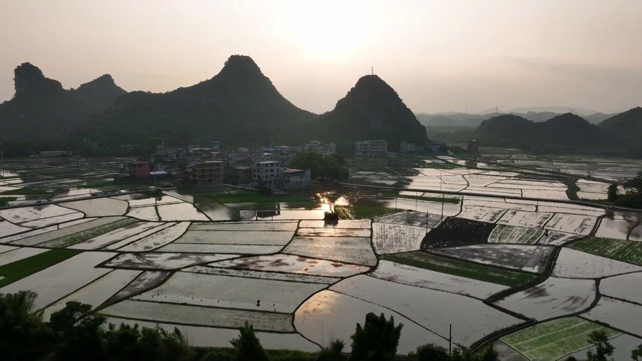 夕阳下山边的村庄和小河边灌满水的田地视频素材