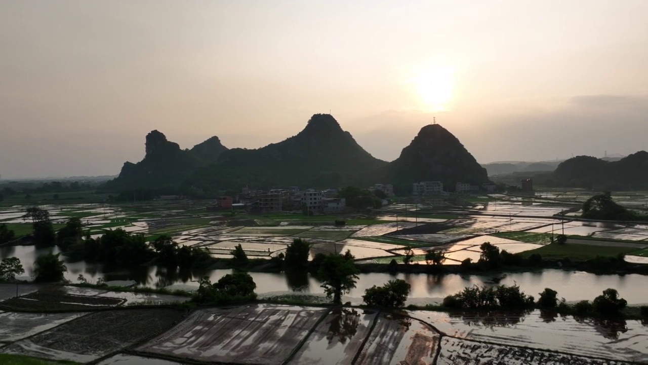 夕阳下山边的村庄和小河边灌满水的田地视频素材