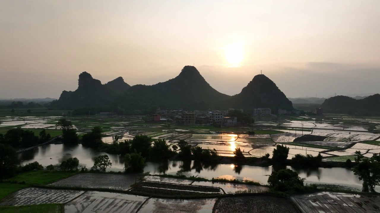 夕阳下山边的村庄和小河边灌满水的田地视频素材