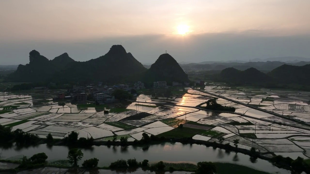 夕阳下山边的村庄和小河边灌满水的田地视频素材