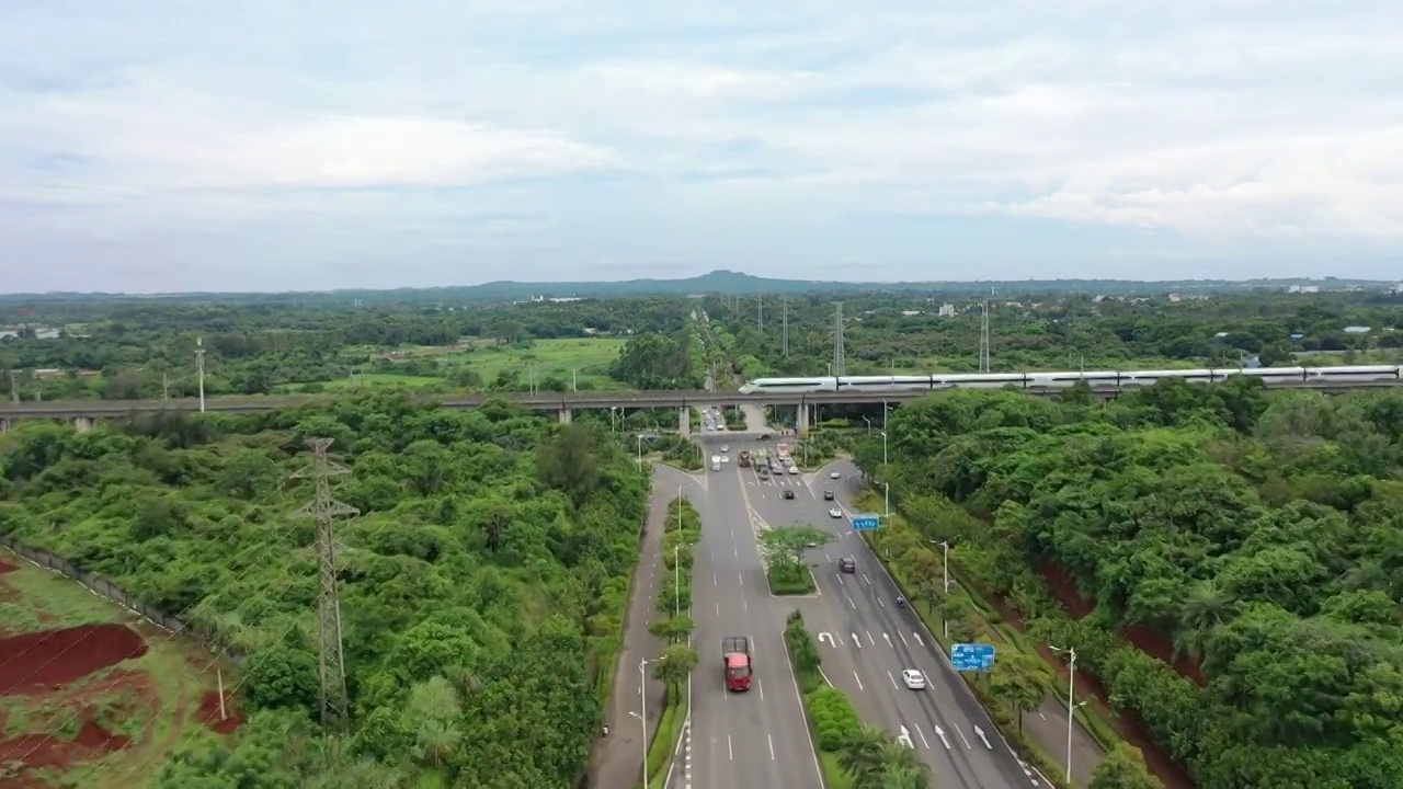 航拍公路镜头高铁动车横穿而过远景是海口火山口公园视频素材