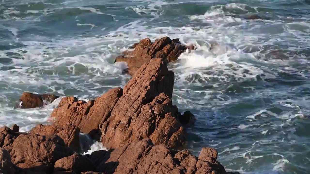 海浪拍打着红色的礁石视频素材