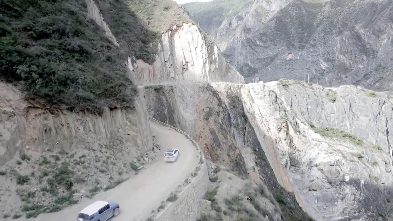 航拍跟进车队走过悬崖边上道路视频素材