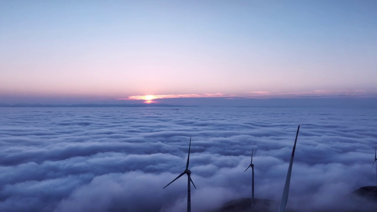 冬季黎明日出时分高山地区的云海和山顶的风力发电风车视频素材