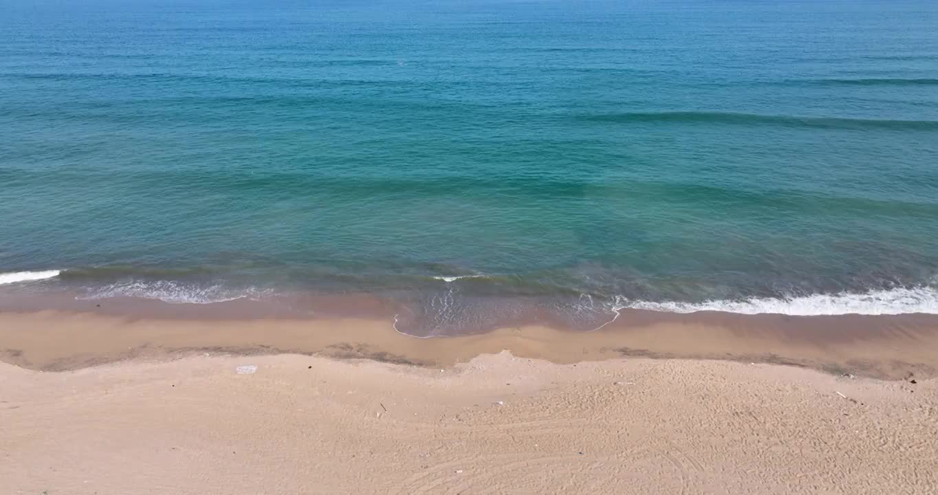 航拍空中鸟瞰海边海浪拍打着岸边的沙滩视频素材