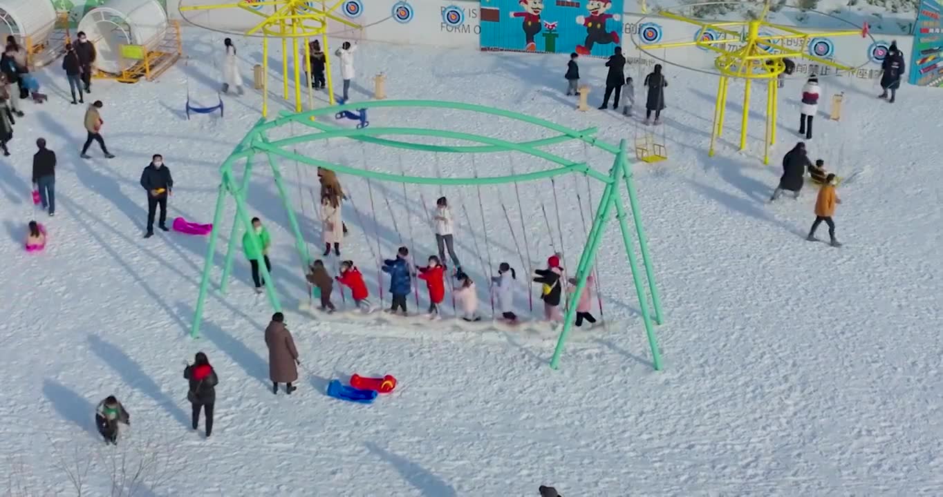 航拍空中鸟瞰滑雪场上市民带着孩子儿童在滑雪玩雪上游戏视频素材画面1