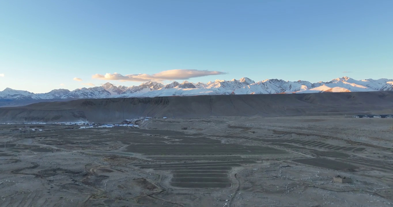 航拍广阔的大地村庄与远处的雪山视频素材