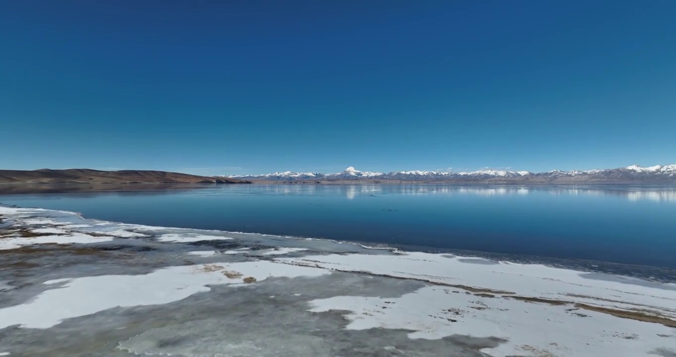 航拍湖水与冰面远处的山峰与地形视频素材