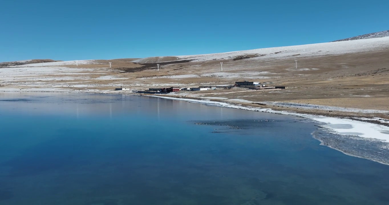 航拍湖水与冰面远处的山峰与地形视频素材