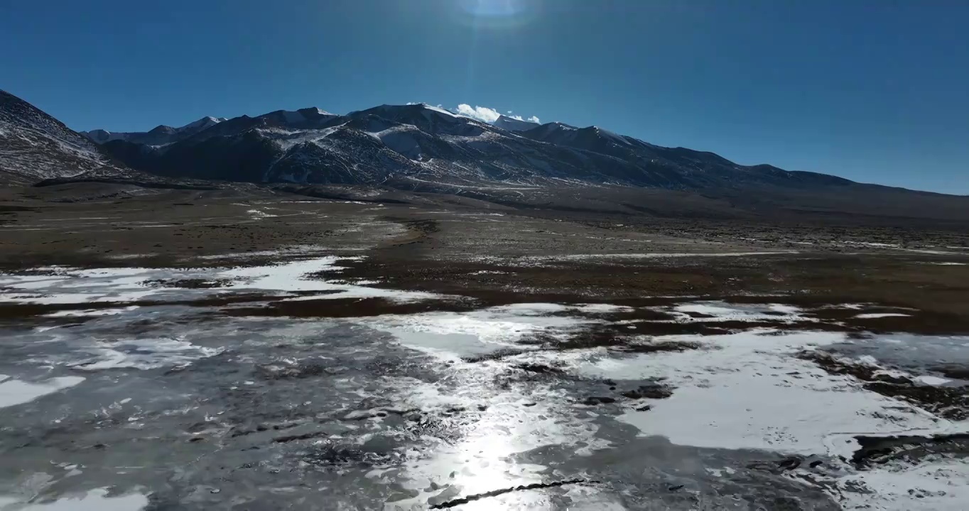 航拍湖水与冰面远处的山峰与地形视频素材