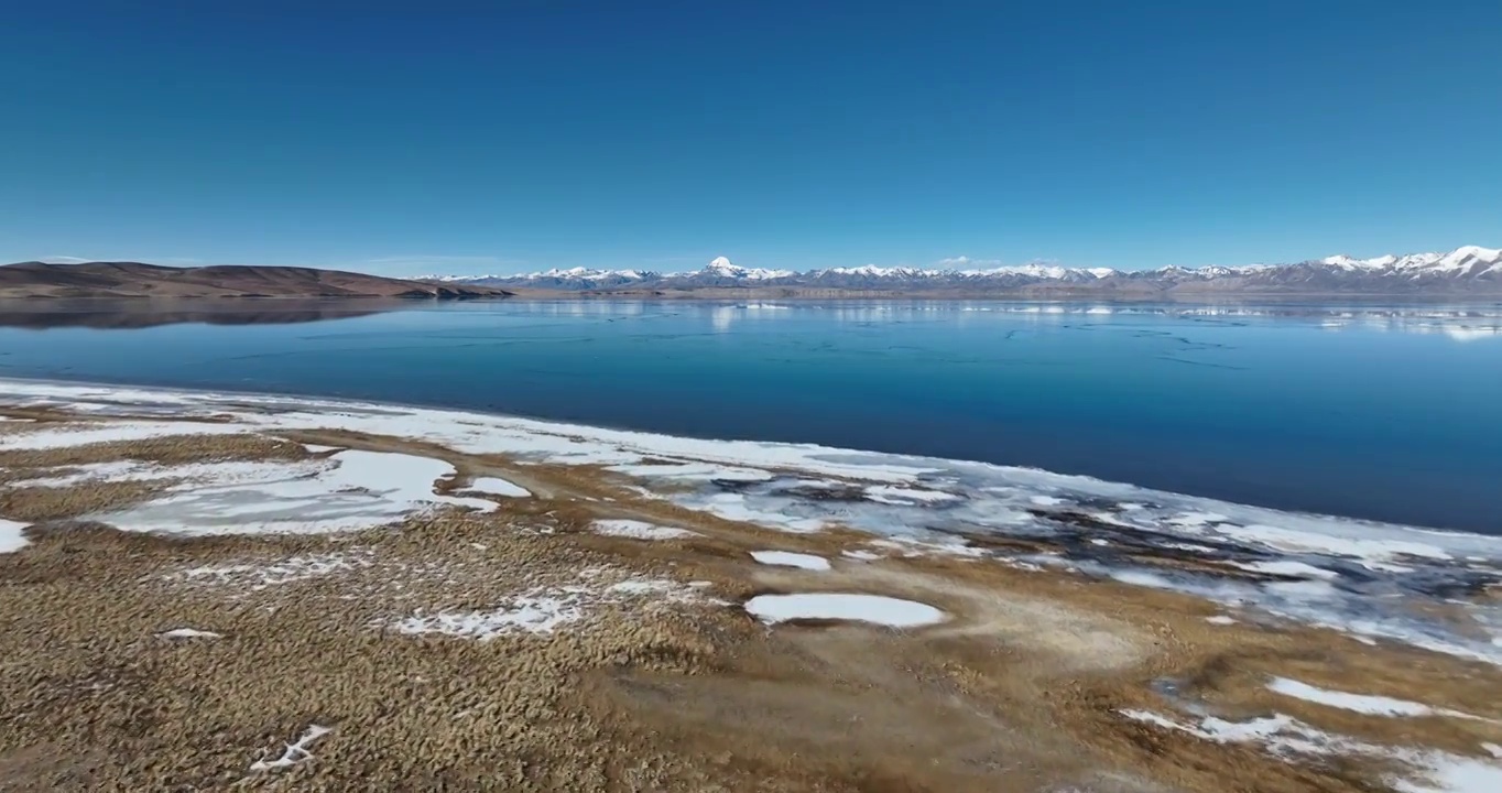 航拍湖水与冰面远处的山峰与地形视频素材