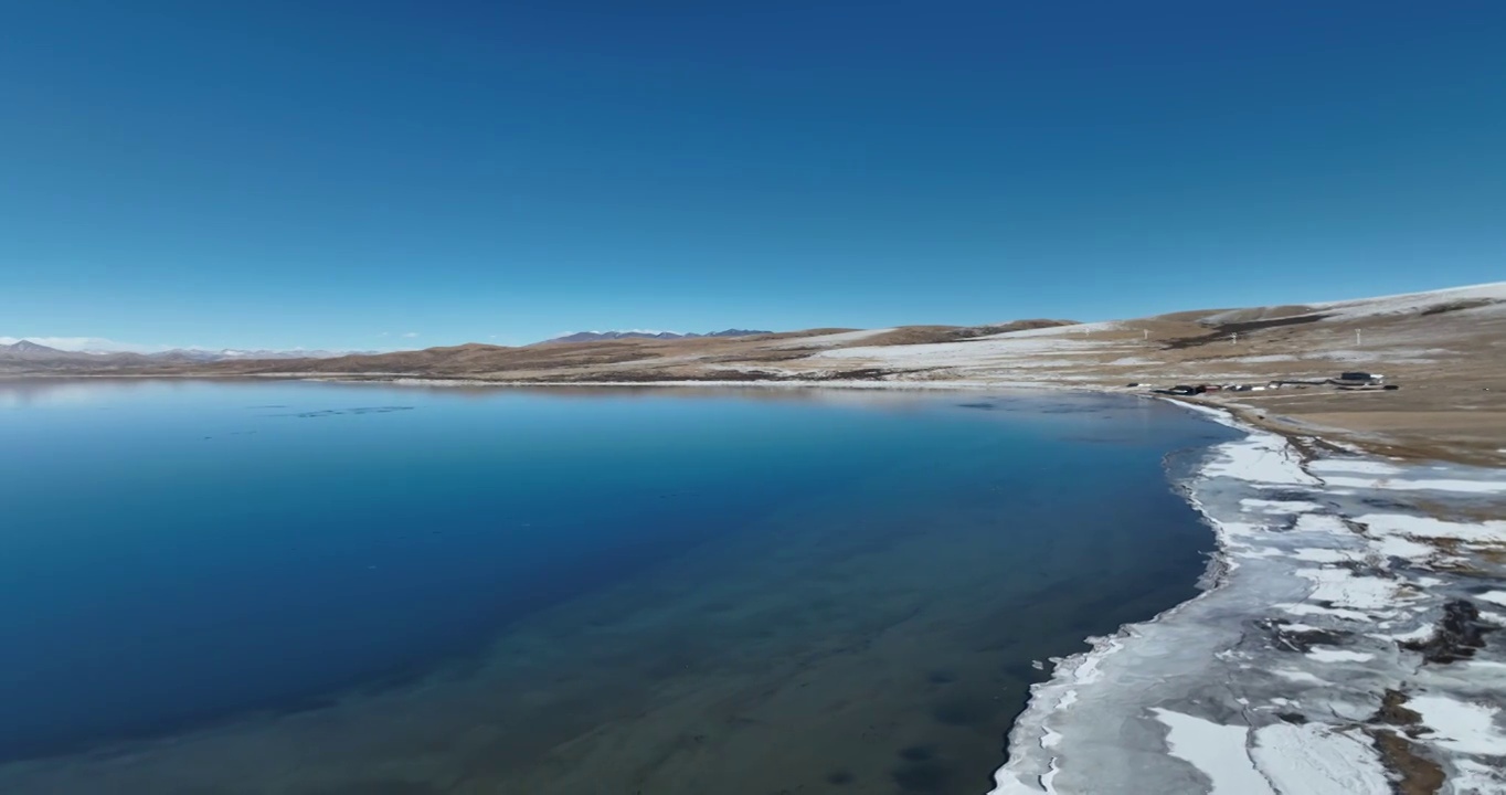 航拍湖水与冰面远处的山峰与地形视频素材