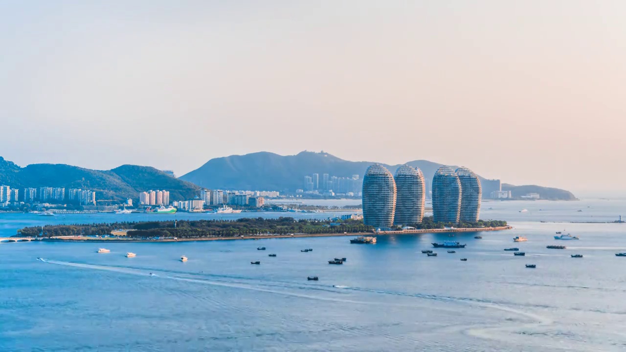 中国海南三亚凤凰岛和穿梭的游艇城市风光延时摄影视频素材