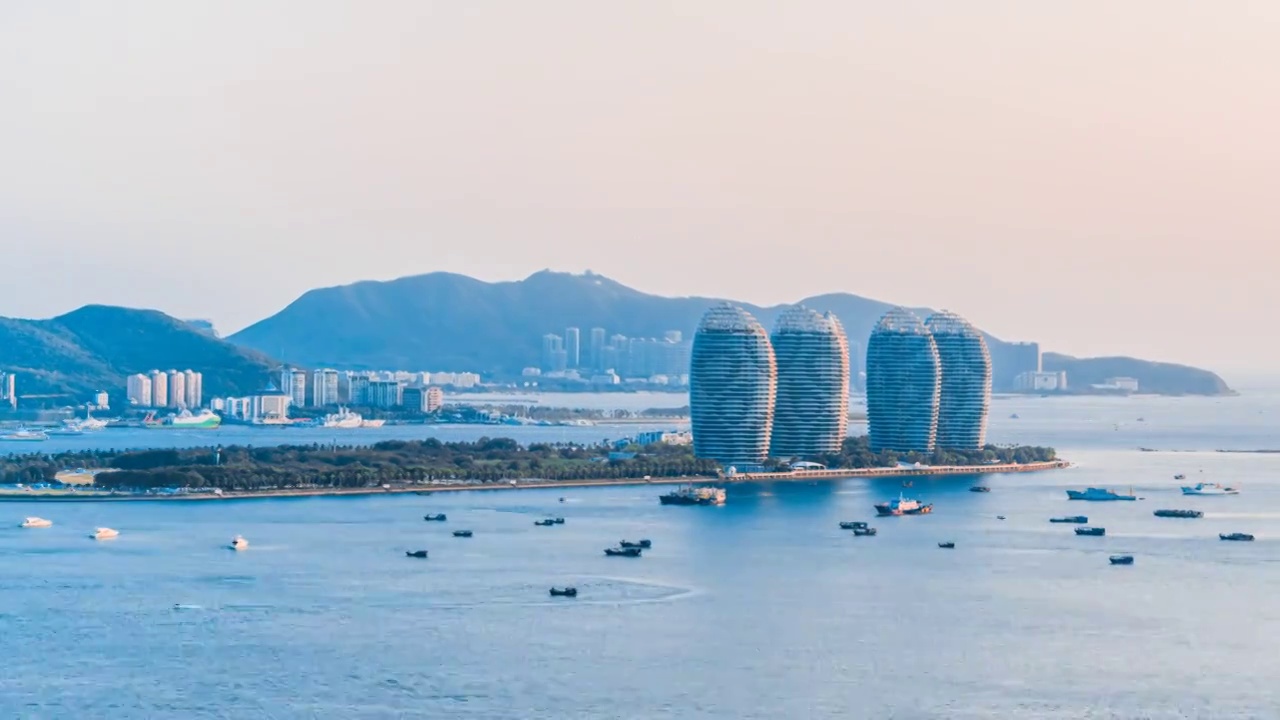 中国海南三亚凤凰岛和穿梭的游艇城市风光延时摄影视频素材