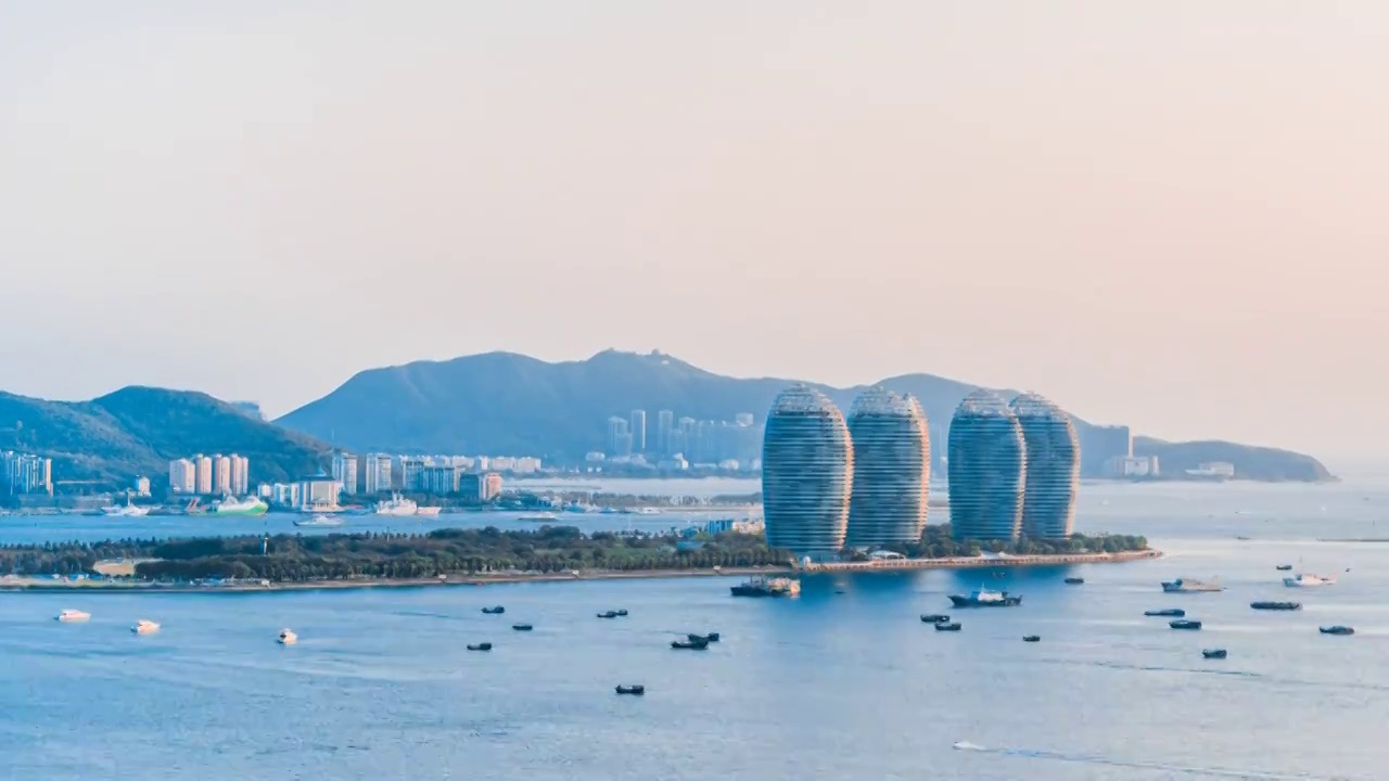 中国海南三亚凤凰岛和穿梭的游艇城市风光延时摄影视频素材