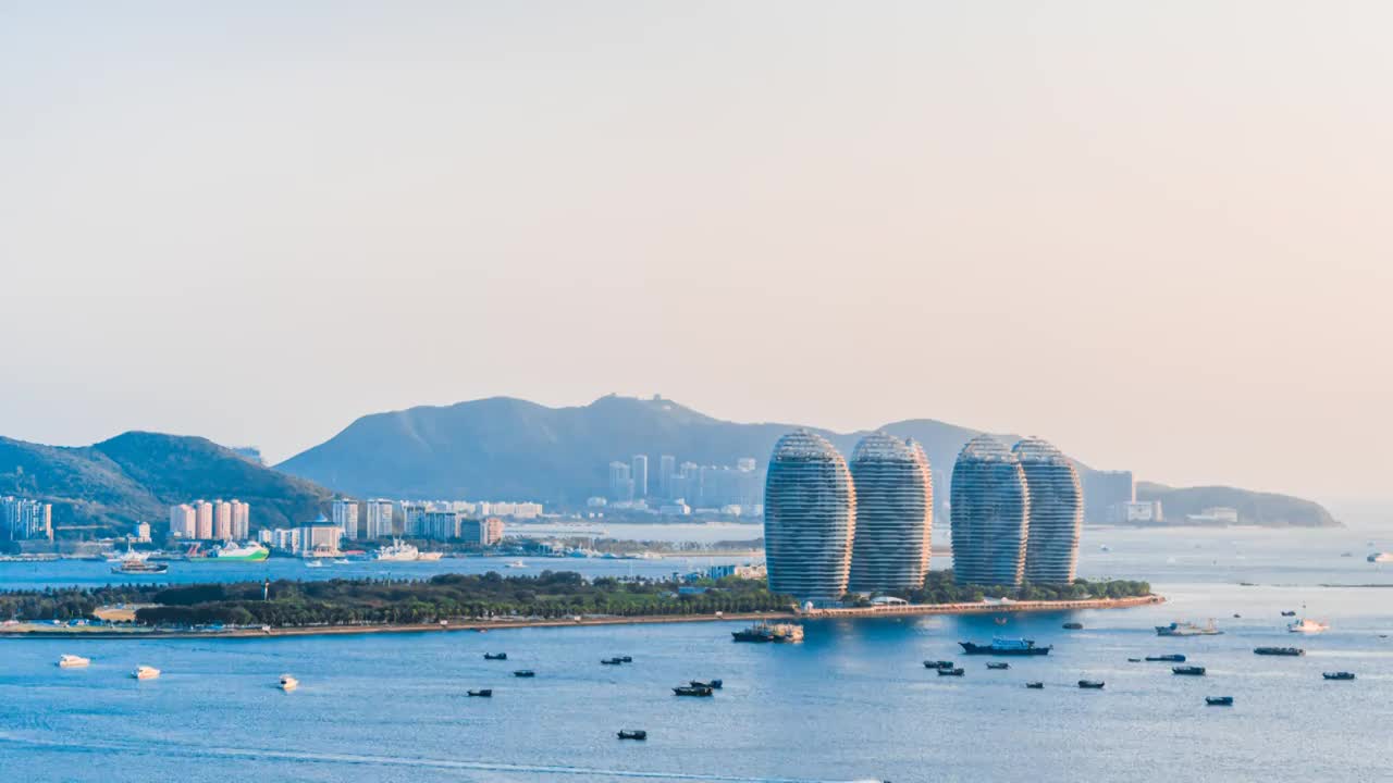 中国海南三亚凤凰岛和穿梭的游艇城市风光延时摄影视频素材