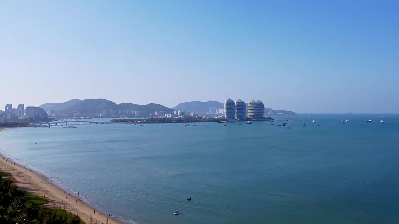 中国海南三亚三亚湾海岸线凤凰岛和城市天际线风光航拍视频素材